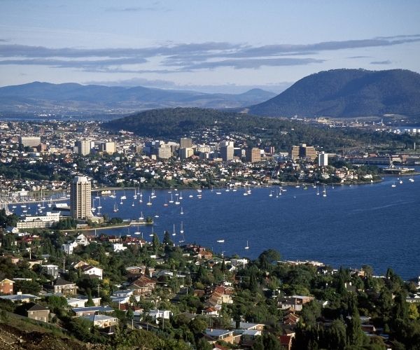 Aerial view of buildings, harbour and blue water of a bay with mountains